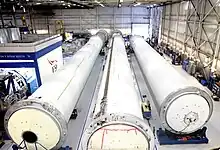 Long, cylindrical rocket sections lie in a warehouse