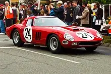 Bright red racing car, number 24, next to a crowd
