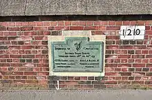 Green plaque mounted on a brick wall