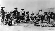 A group of 14 armed men, eight of them crouching down, in sombreros and holding rifles