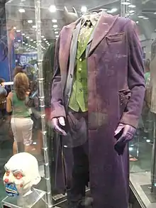 A photograph of Heath Ledger's Joker costume in a display case alongside his mask used to rob a bank