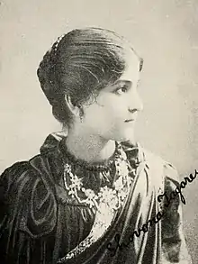 Young woman looking to the right, wearing a high-necked dark dress, a gemstone necklace, and a light-colored sash. Her name, Shovona Tagore, is signed in the lower right.