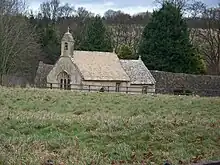 A small, simple church seen from a distance showing the nave with a single bellcote, and a smaller chancel beyond