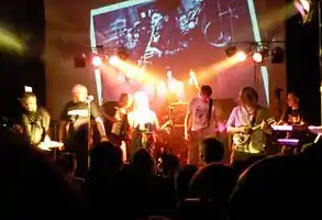 The Tansads on stage at one of their 2010 reunion gigs. Visible from left to right: John Kettle, Andrew Kettle, Dominic Lowe, Janet Anderton, Phill Knight, Ed Jones, Bob Kettle, Lee Goulding