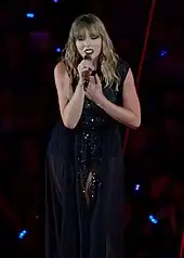 Taylor Swift performing while dressed in a black dress