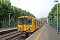 A Merseyrail Class 507 waits at the station.