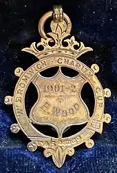 ornate gold medal with maker's mark and hallmark as described in caption, and inscription which reads "W. Bromwich Charity cup - 1901-2 - E. Wood"