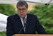 William Barr speaking at a podium