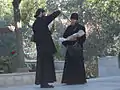 Um clérigo ortodoxo russo próximo a Ein Carem, Jerusalém. Cada um está usando um podryasnik e batina. O hieromonge (à direita) está usando skoufos e uma cruz peitoral