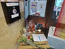 Foto de uma mesa com foto de Brianna Ghey, rosas vermelhas e um livro de condolências.