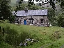 Uma fotografia a cores de uma casa de pedra em uma colina.