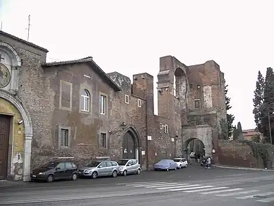O edifício na extremidade à esquerda é a antiga entrada do hospital de San Tommaso, com o famoso mosaico de "Cristo libertando os escravos" (ao lado). No fundo, o Arco de Dolabela, incorporado na Água Cláudia.