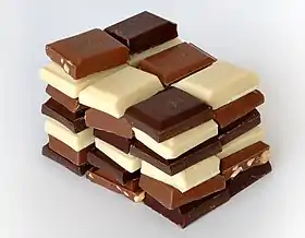 Três tipos de chocolate: chocolate branco (branco), chocolate ao leite (mais claro) e chocolate amargo (mais escuro)