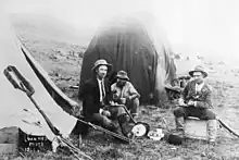 Een foto van Louis Wessels (links) met twee andere mannen voor een tent.