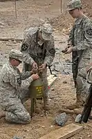 Uma munição de carga em forma de 40 lb (18 kg) (marcada para indicar um enchimento de Composição B) usada para vários fins de demolição, como abrir um buraco para uma carga de cratera.