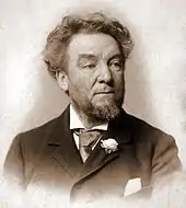 A bearded man wearing a suit and a tie