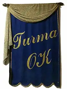 Flâmula original do clube social Turma OK, confeccionada em veludo com letras em detalhes ouro