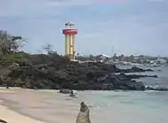 Vista do farol de Puerto Baquerizo Moreno, com um leão-marinho em primeiro plano.