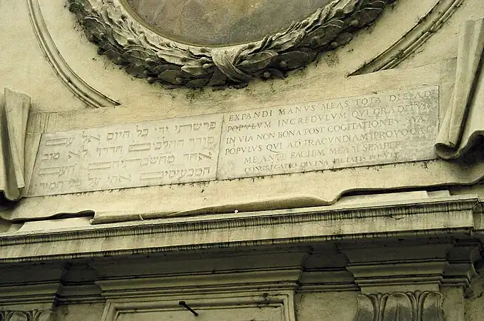 Inscrição bilíngue de Isaías 65:2–3 na fachada, uma admoestação aos judeus