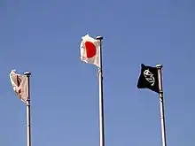 Três bandeiras tremulam no céu.