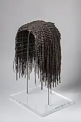 foto de uma peruca em um suporte que simula uma cabeça para dar sustentação.