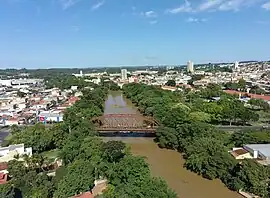 Ponte Metálica vermelha sobre Rio Mojiguaçu, ao fundo; vista do centro da cidade International Paper