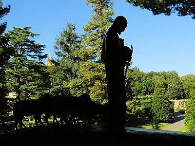 Imagem de Jesus, como pastor de ovelhas, com janela para o jardim dos Museus Vaticanos ao fundo.