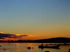 Retângulo AZUL ESCURO - Semicírculo superior LARANJA - Triângulo central BRANCO - Dento do triângulo há um Mandacaru VERDE e uma Lua AMARELA abaixo do mandacaru.