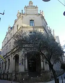 Edifício Central dos Correios de Pontevedra na rua com a oliveira em frente ao edifício.