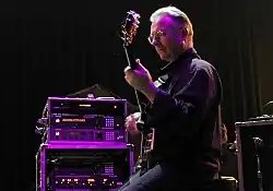 Robert Fripp ergonomically plays electric guitar while sitting in a posture developed through years of application of the Alexander Technique.