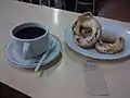 Xícara de café servido com rosquinhas espanholas.