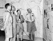 Four men in summer military uniforms in front of a map of northern Australia