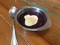 Sagu de vinho com creme e canela em um pote com uma colher