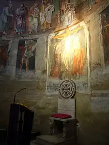 Abside decorada com antigos afrescos e uma cátedra.