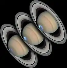 Três fotografias de Saturno justapostas, em que o planeta aparece com coloração bege e os anéis de formato elíptico circulam o planeta. Na parte inferior das três imagens, manchas azul claro de formato circular com diferentes intensidades.