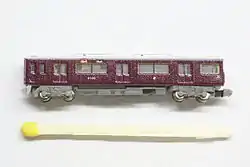 Modelo do vagão Hankyu 9000 na escala T com um palito de fósforo para comparar o tamanho.