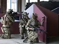 Três membros da equipe de airsoft defendendo uma área durante um jogo CQB interno.