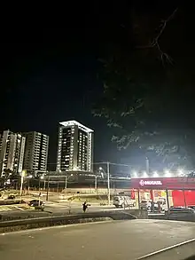 A imagem mostra edifícios de um Bairro da cidade de Uberlândia durante a noite com luzes acesas.