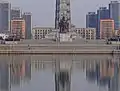A parte inferior da Torre da Ideologia Juche, com o rio Taedong em primeiro plano e edifícios simétricos em segundo plano.