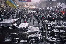 Manifestantes junto a veículos queimados na rua Dynamivska em Kiev, janeiro de 2014