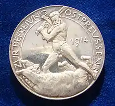 O inverso da libertação da medalha de prata alemã durante a Primeira Guerra Mundial da Prússia Oriental, 1914, por Paul von Beneckendorff und von Hindenburg. Referindo-se à Batalha de Tannenberg. O general Hindenburg nu lutando com o urso russo com sua espada.