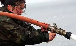 A woman using a fire hose.